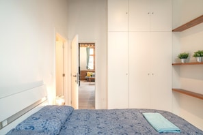Ein Schlafzimmer mit einem Bett, einem Kleiderschrank und einem kleinen Regal mit Pflanzen.