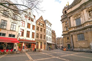 Ein Kopfsteinpflasterplatz mit historischen Gebäuden, einem Café und einem Radfahrer.