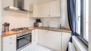 A modern kitchen with white cabinets, a gas stove, an oven, a microwave, and a sink.