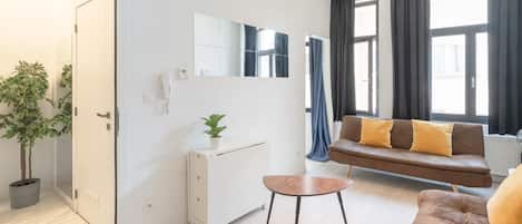 A modern living room with a sofa, a small table, a potted plant, and a built-in cabinet.