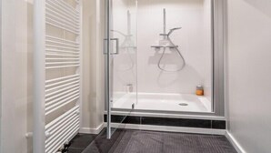 A modern shower enclosure with a glass door, a built-in bench, and a handheld showerhead.