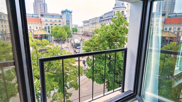 A cityscape through a window with a view of buildings, a street, and trees.