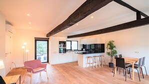 A modern kitchen with white cabinets, a black countertop, and a wooden ceiling beam.