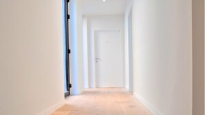 A hallway with a wooden floor and white walls.