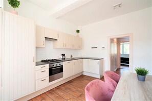 Une cuisine moderne avec des meubles blancs, une cuisinière à gaz et un plancher en bois.