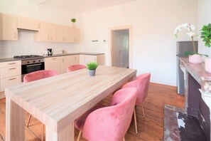 Eine moderne Küche mit einem Holztisch, rosafarbenen Stühlen, einem Herd und Schränken.