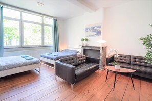 Une pièce comprenant un lit, deux canapés, une petite table, une cheminée et une fenêtre avec des rideaux.