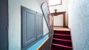 A staircase with a wooden handrail, a red carpeted landing, and a small potted plant on a wooden table. - Old town lodge Antwerp Apartment (Antwerp)