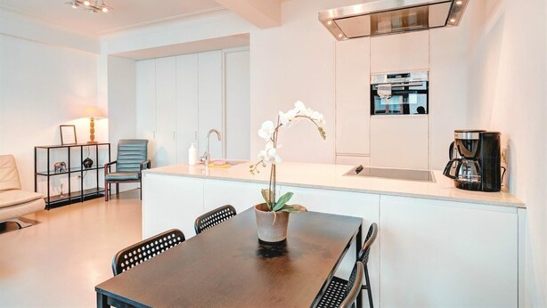 A modern kitchen with white cabinetry, a built-in oven, and a coffee maker on the counter. - Family Retreat with Balcony in Meir (Antwerp)