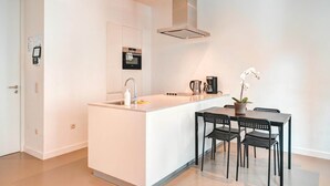 A modern kitchen with a central island, a built-in oven, and a coffee maker. - Family Retreat with Balcony in Meir (Antwerp)