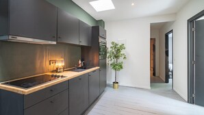Una cocina moderna con armarios oscuros, estufa empotrada y una planta en maceta.