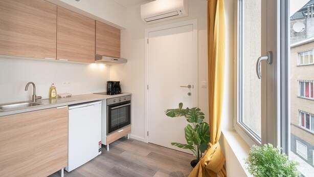 Uma cozinha moderna com máquina de lavar louça, forno e janela com cortinas.