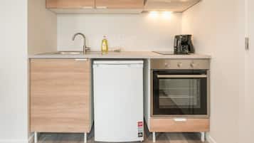 Een koffiezetapparaat/waterkoker, een koelkast, een oven, een kookplaat