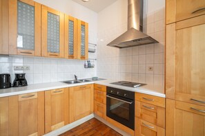 Eine Küche mit Holzschränken, einer Edelstahl-Dunstabzugshaube, einem Kombi-Backofen und einer weißen Arbeitsplatte.