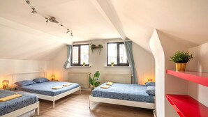 Ein Zimmer mit zwei Betten, einem roten Regal und einer Pflanze.
