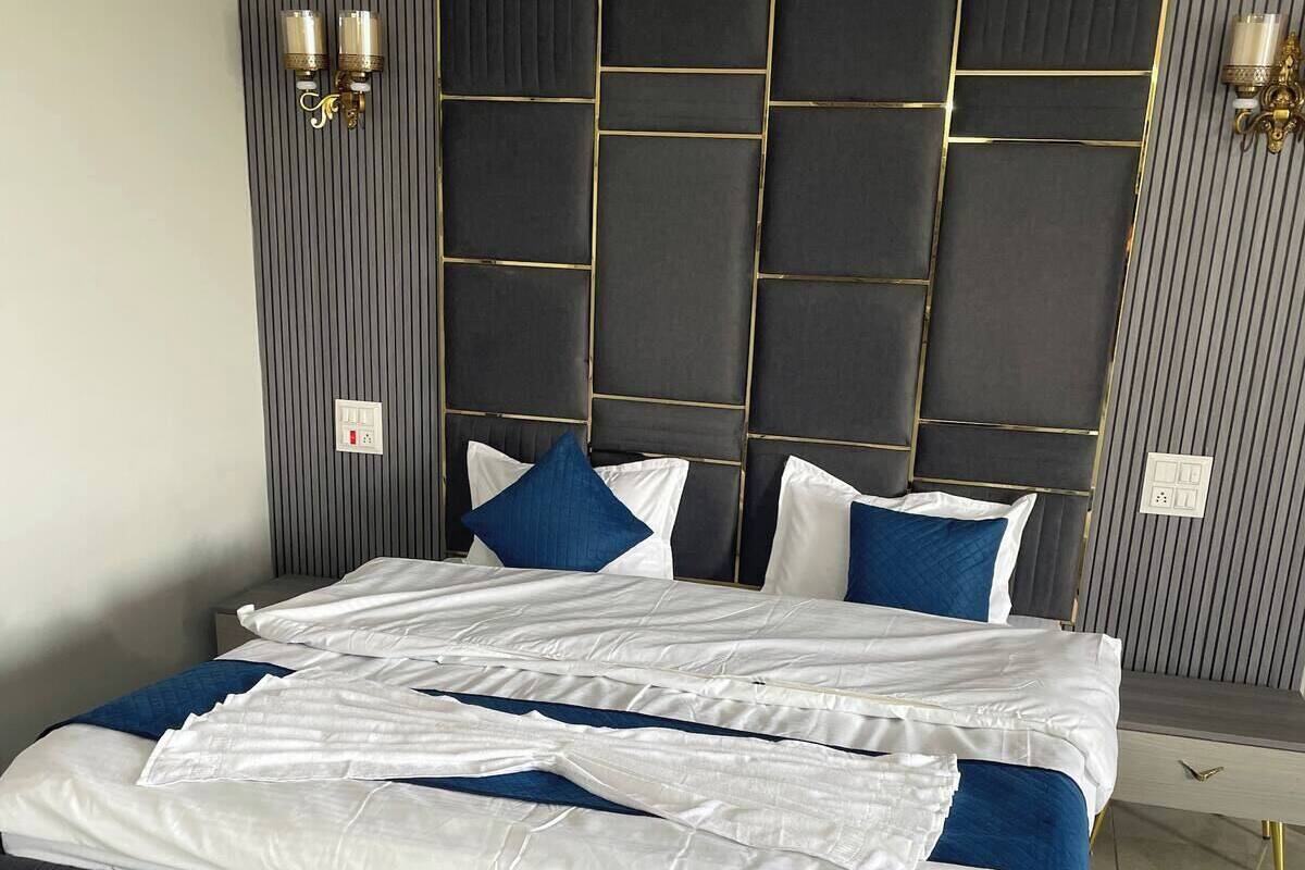 A modern bedroom with a large bed, a headboard with a geometric pattern, and two wall-mounted light fixtures.