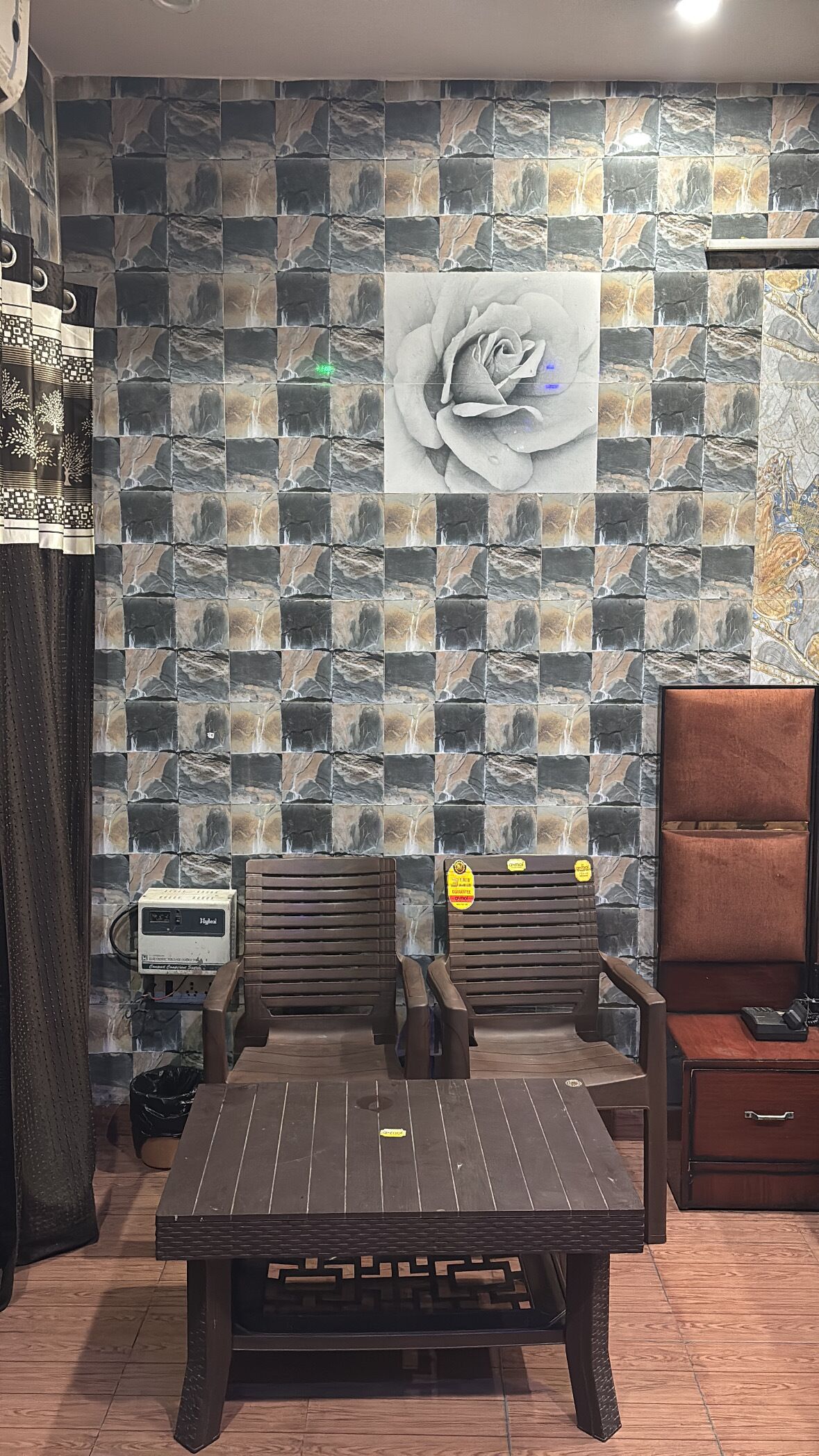 A room with a patterned wall, a bed, a table, a chair, and a cabinet.