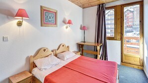 A bedroom with a wooden bed, two bedside tables, a desk, a framed picture, and a window with curtains. - Spacious Mountain Stay for 7 (Risoul)