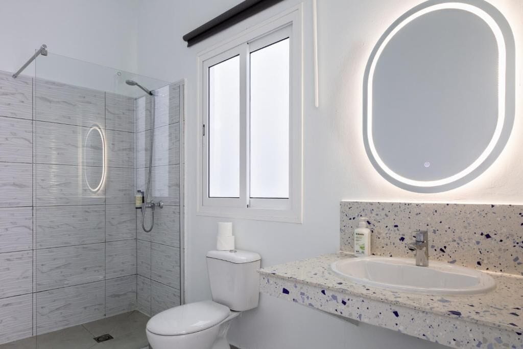 A modern bathroom with a shower, toilet, and sink.