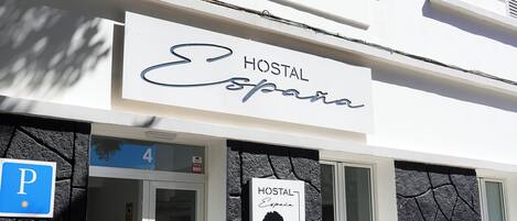Un edificio con un letrero que dice 'HOSTAL España' y una señal de estacionamiento.