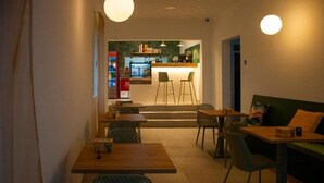 A cozy cafe with a counter, stools, and tables. - Hostal España (Arrecife)