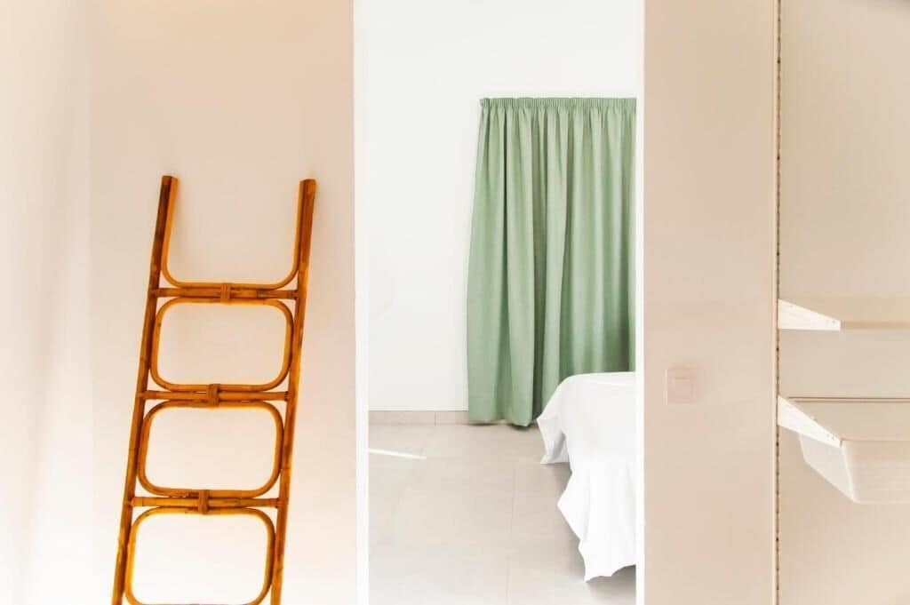 A room with a bed, a green curtain, and a white wall.