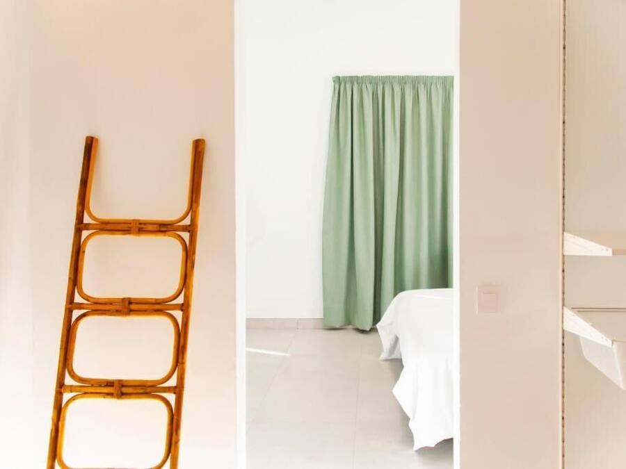Una habitación con una cama, una cortina verde y una pared blanca.