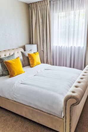 Ein Schlafzimmer mit einem gesteppten Kopfteil, einem Bett mit weißer Bettwäsche und zwei gelben Kissen.