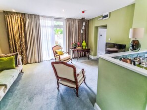 A living room with a sofa, two armchairs, a small table with a vase, and a television. - The Mews by Interhome (Torquay)