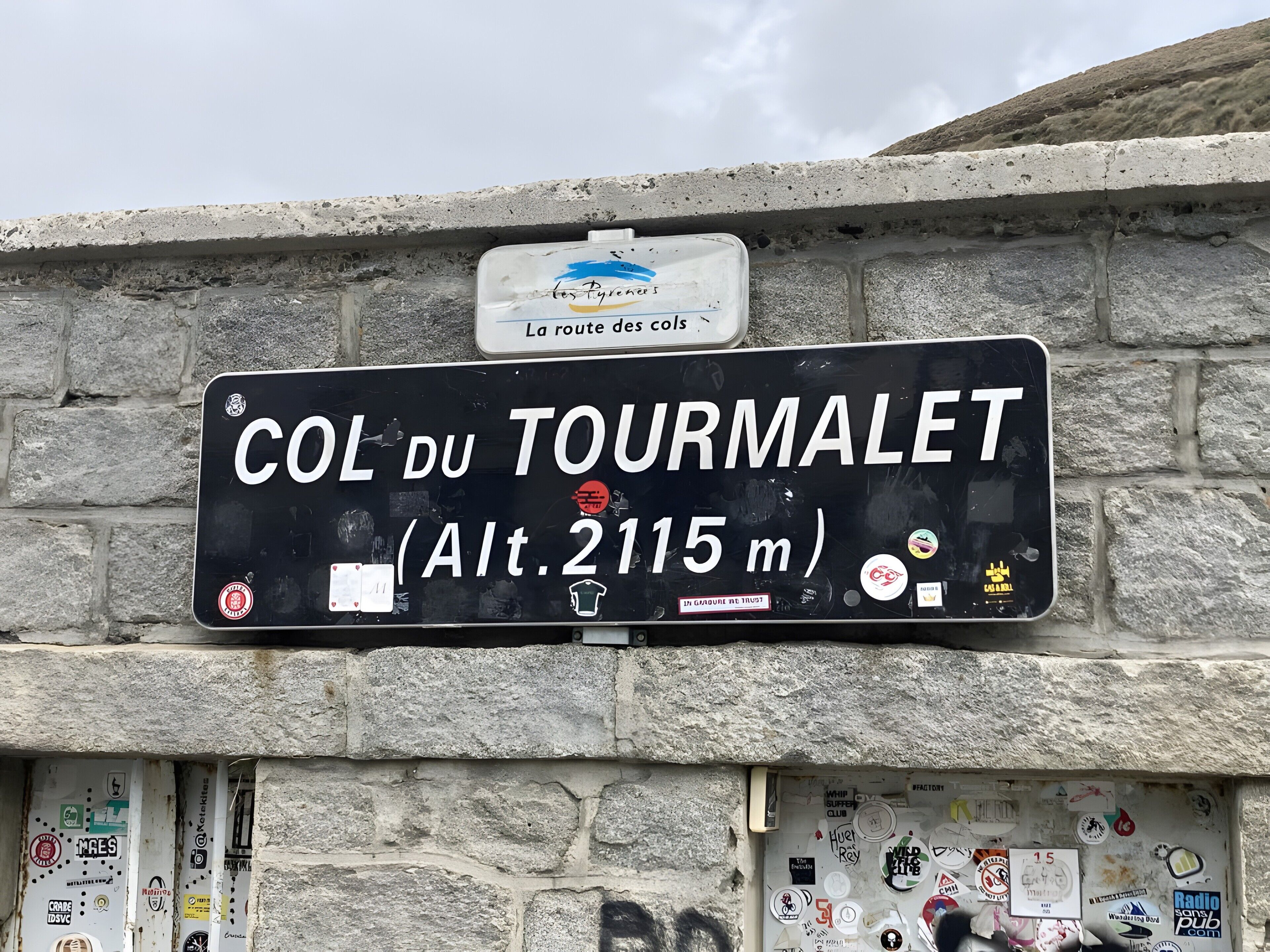 A sign with 'COL DU TOURMALET' and an altitude of 2115m.