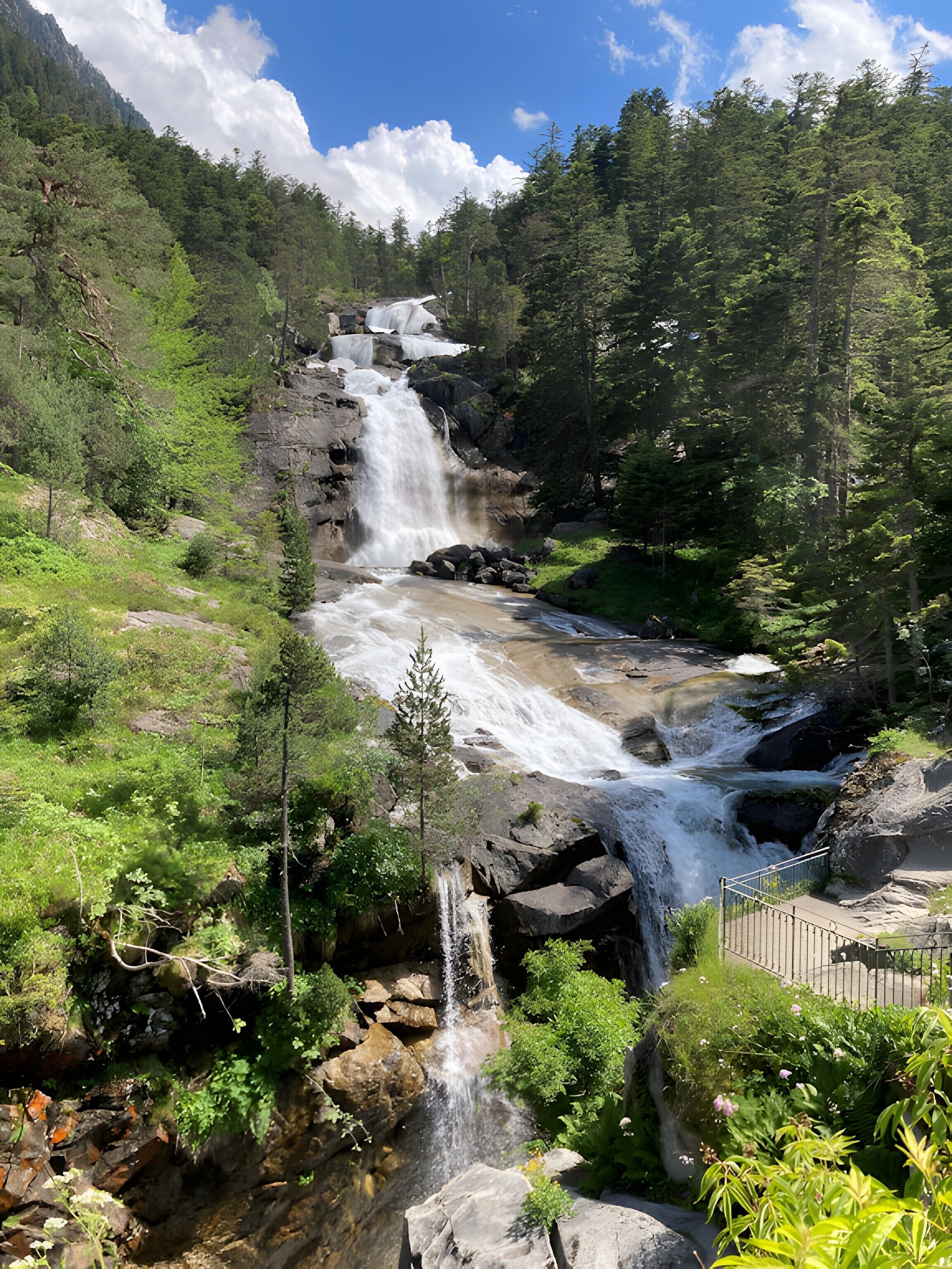 A waterfall cascading over rocks in a forested area with a clear sky.