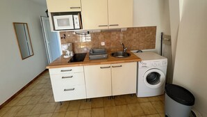 Cocina compacta con microondas, cafetera, lavabo y lavadora.