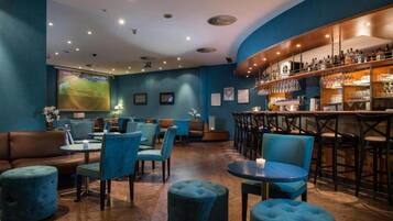 A bar area with seating, a television screen, and a bar stocked with bottles.