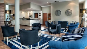 A modern living room with a sofa, chairs, a coffee table, and a kitchen area in the background.