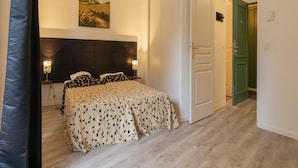 A bedroom with a bed, two bedside lamps, a painting on the wall, and a door leading to another room. - Apartment in Grasse Near Restaurants (Grasse)