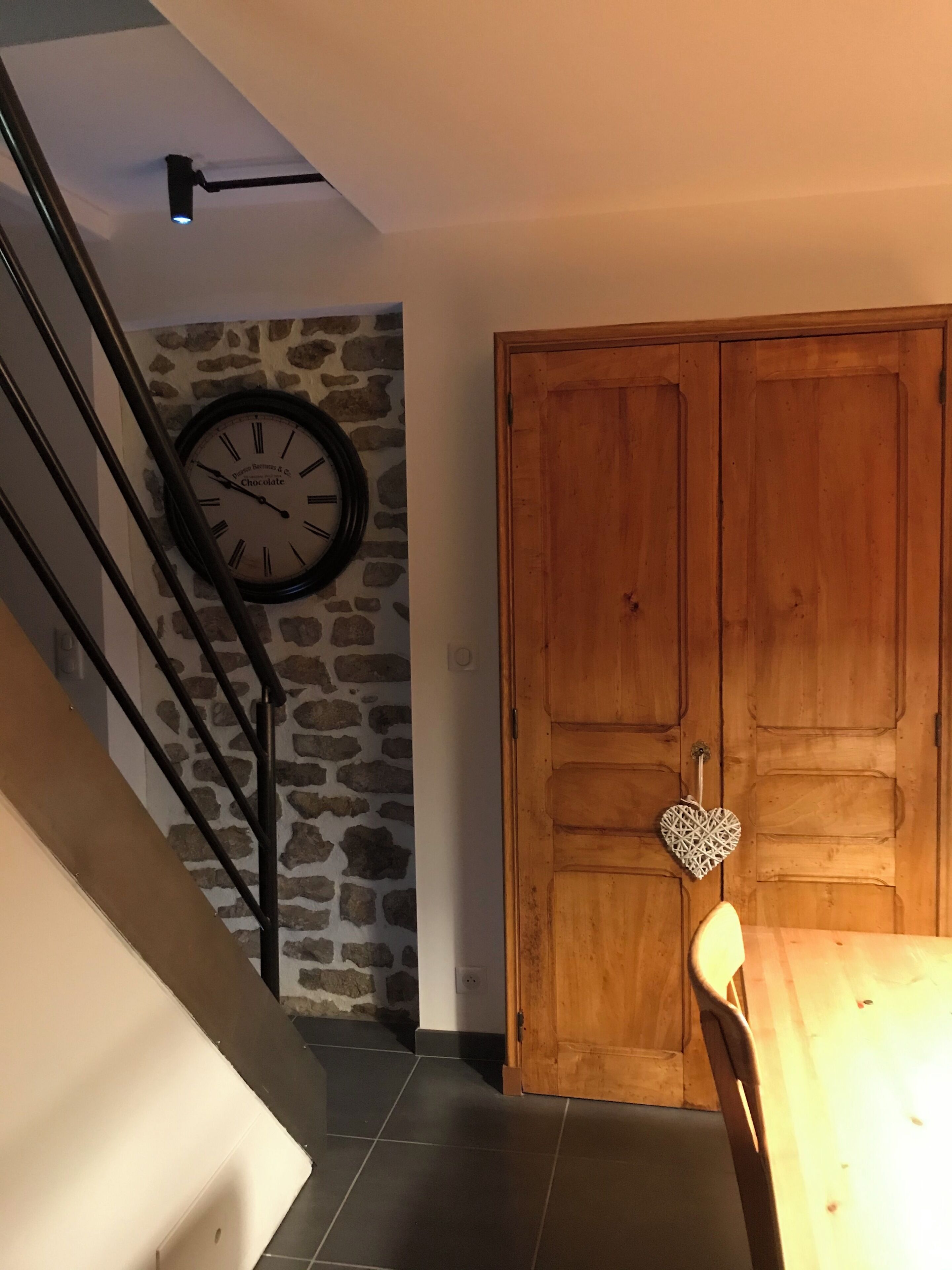 A staircase with a stone wall, a wooden door, and a wall clock.