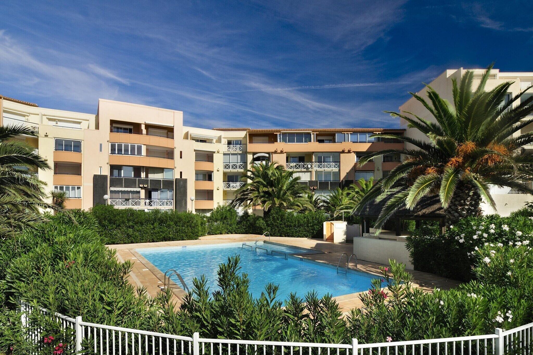 A hotel with a swimming pool surrounded by greenery and palm trees.