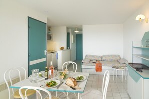 Ein kompakter Wohnbereich mit Essplatz, Küchenzeile und Sofa.