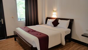 A neatly made bed with a white and maroon bedspread, a wooden headboard, and a wall-mounted light fixture. - STC Hotel School (Siem Reap)