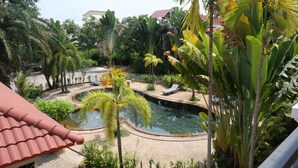 A swimming pool surrounded by tropical plants, with lounge chairs and a curved pathway. - STC Hotel School (Siem Reap)