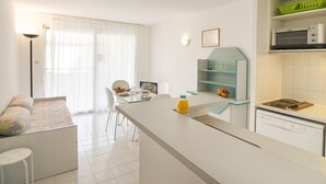 Una cocina compacta con microondas, lavavajillas y comedor con mesa y sillas.