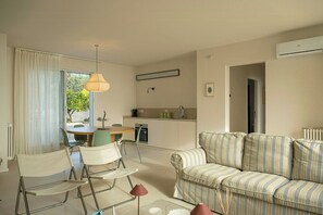A modern living room with a sofa, chairs, a dining table, and a kitchen area.
