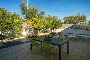 An outdoor patio with a table and chairs, surrounded by trees and a fence.
