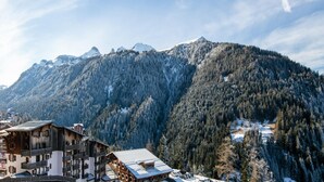 A mountain village with traditional wooden buildings, a ski slope, and snow-covered peaks. - Alpine Comfort Apartment Near Ski-slopes (Modane)