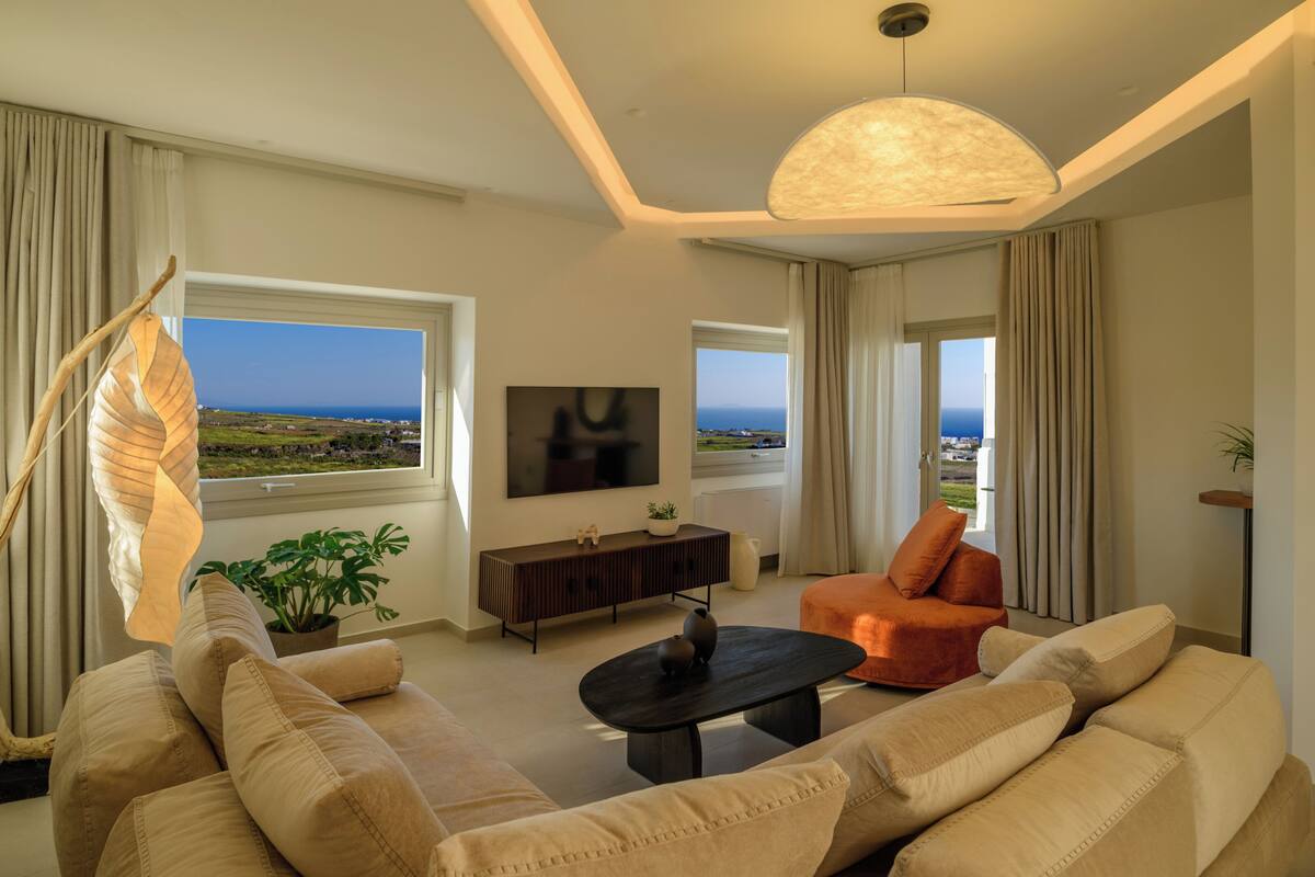 Una sala de estar moderna con sofá, mesa de centro, televisor y vista al océano.