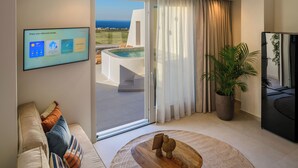 Un salon moderne doté d’un grand téléviseur, offrant une vue sur la piscine, et comprenant un coin salon confortable.