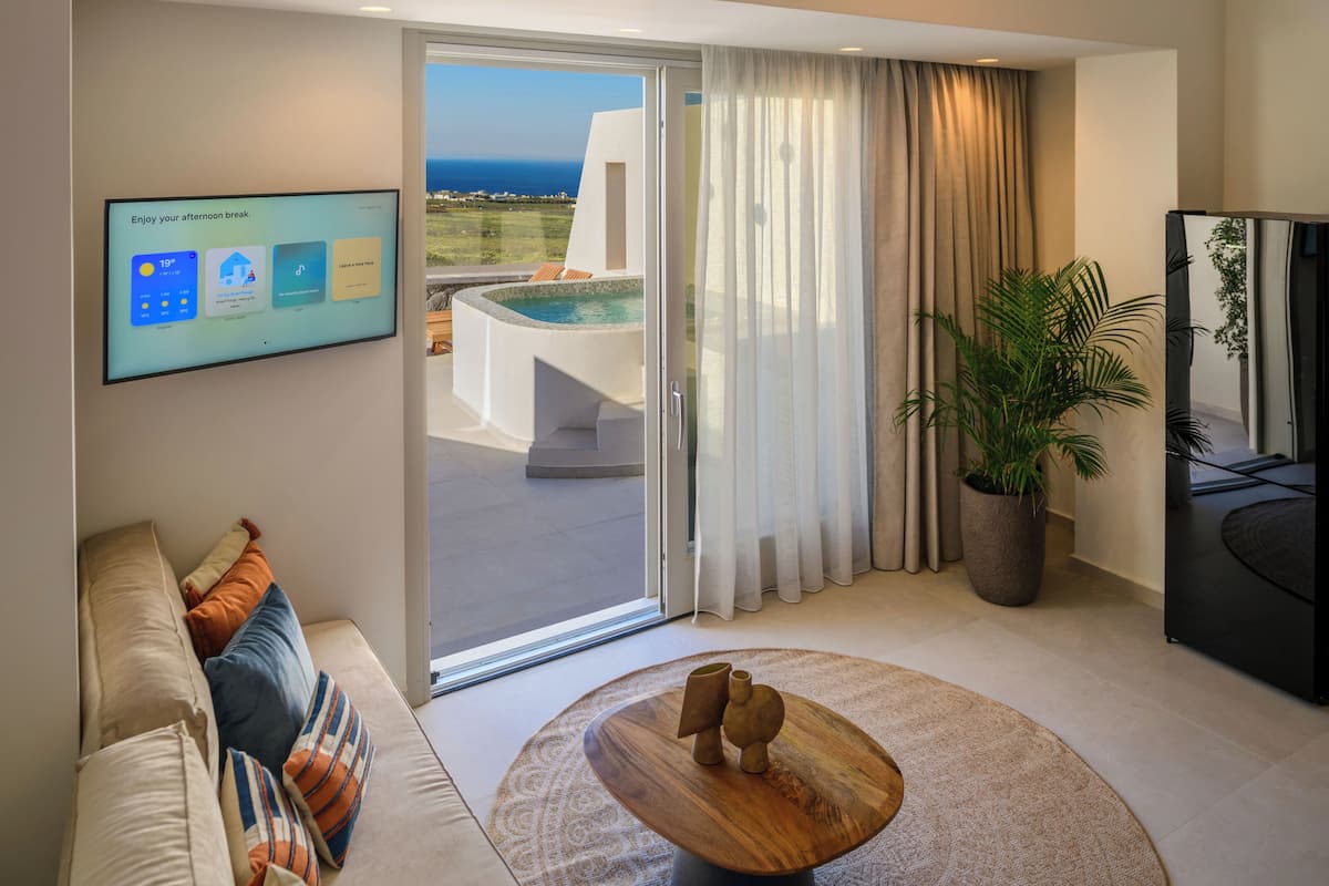 Una sala de estar moderna con un televisor grande, vistas a la piscina y una zona de estar acogedora.