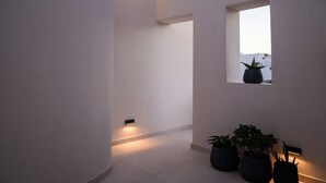 Un intérieur moderne avec un mur incurvé, une petite fenêtre et des plantes en pot.