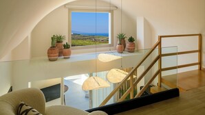 Un intérieur moderne avec un escalier en verre, une vue sur la mer et des plantes en pot sur un balcon.