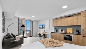 A modern apartment with a large window, a dining area, a kitchenette, and a living space with a sofa and a laptop. - 501 First Studio with Luxury Amenities (Miami)